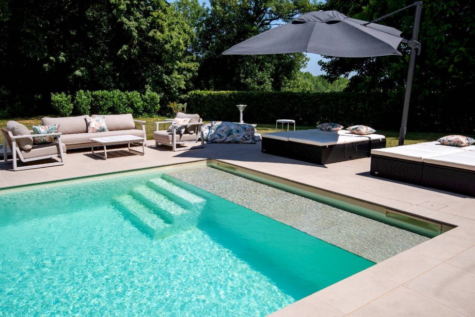 Zoom sur les marches latérales et la plage immergée de la piscine Mondial Piscine à Buellas