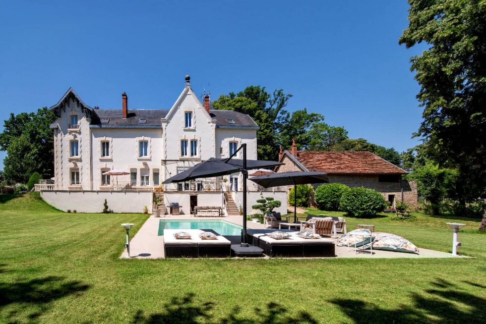 Intégration d'une piscine Mondial Piscine devant une demeure rénovée à Buellas, avec transats, parasols et aménagement paysager