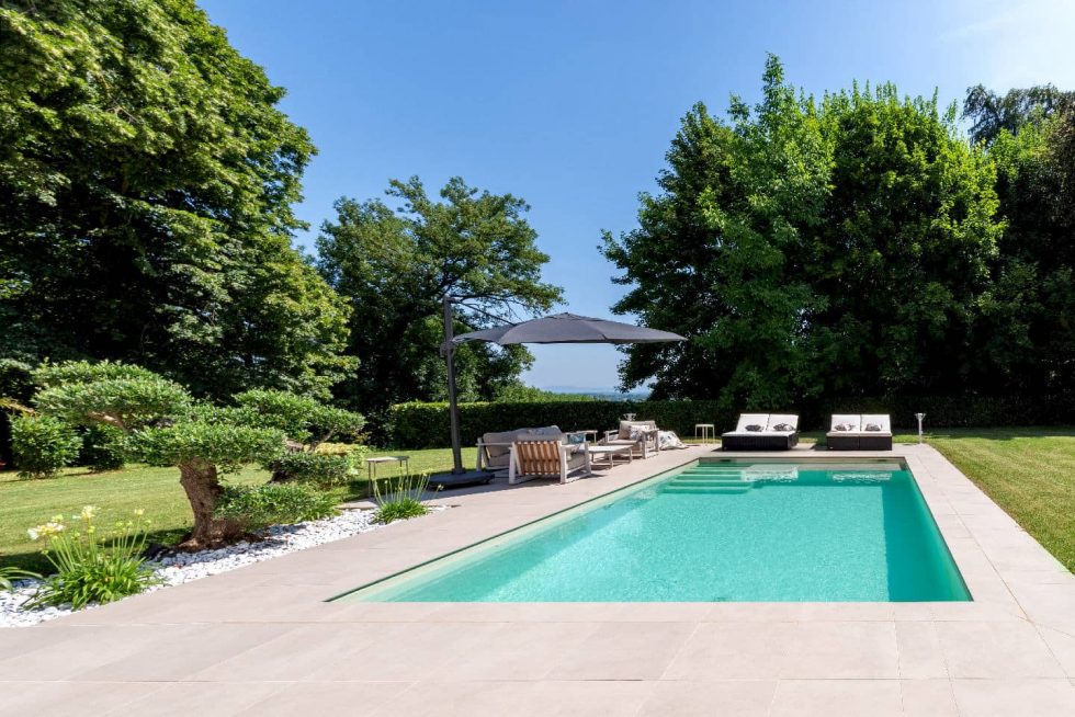 Piscine béton Mondial Piscine avec escalier sur la largeur, fond plat 1m50, plage immergée et vue dégagée sur le jardin à Buellas