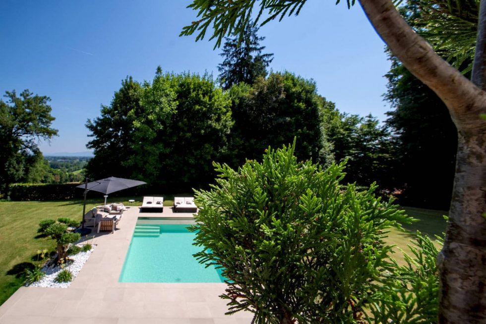 Piscine contemporaine entourée de verdure et d’un jardin arboré, projet réalisé à Buellas, aux portes de Bourg-en-Bresse