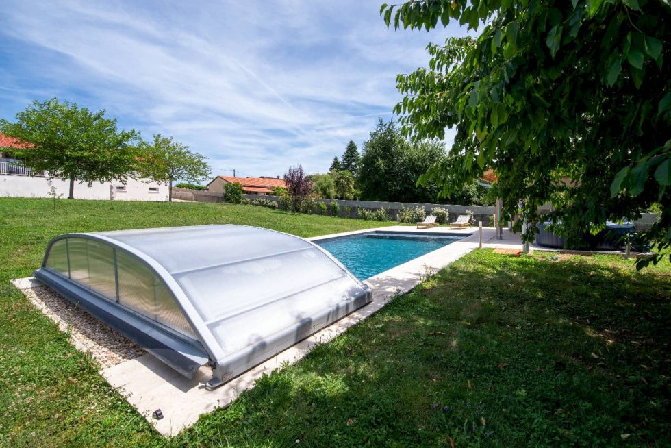 Pelouse arborée et bains de soleil installés autour du bassin