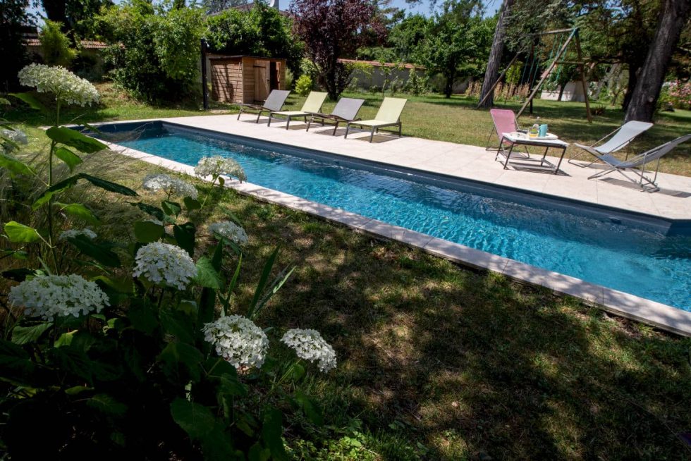 Vue d'ensemble de la piscine couloir de nage avec fleurs et arbres, créant un cadre naturel et relaxant à Beynost