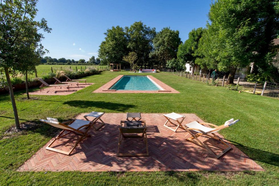 Coin détente avec chaises longues et vue dégagée sur la piscine en briques