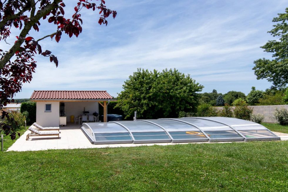 Le pool house carrelé avec espace repas à côté de la piscine